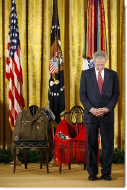 President George W. Bush bows his head during a prayer Monday, March 3, 2008 in the East Room of the White House, standing before two chairs in honor of U.S. Army Master Sgt. Woodrow Wilson Keeble, left, and his wife, Bloosom, moments before presenting members of the Keeble family with the Medal of Honor, posthumously, in honor of Master Sgt. Keebles gallantry during his service in the Korean War. Keeble is the first full-blooded Sioux Indian to receive the Medal of Honor. White House photo by Eric Draper
